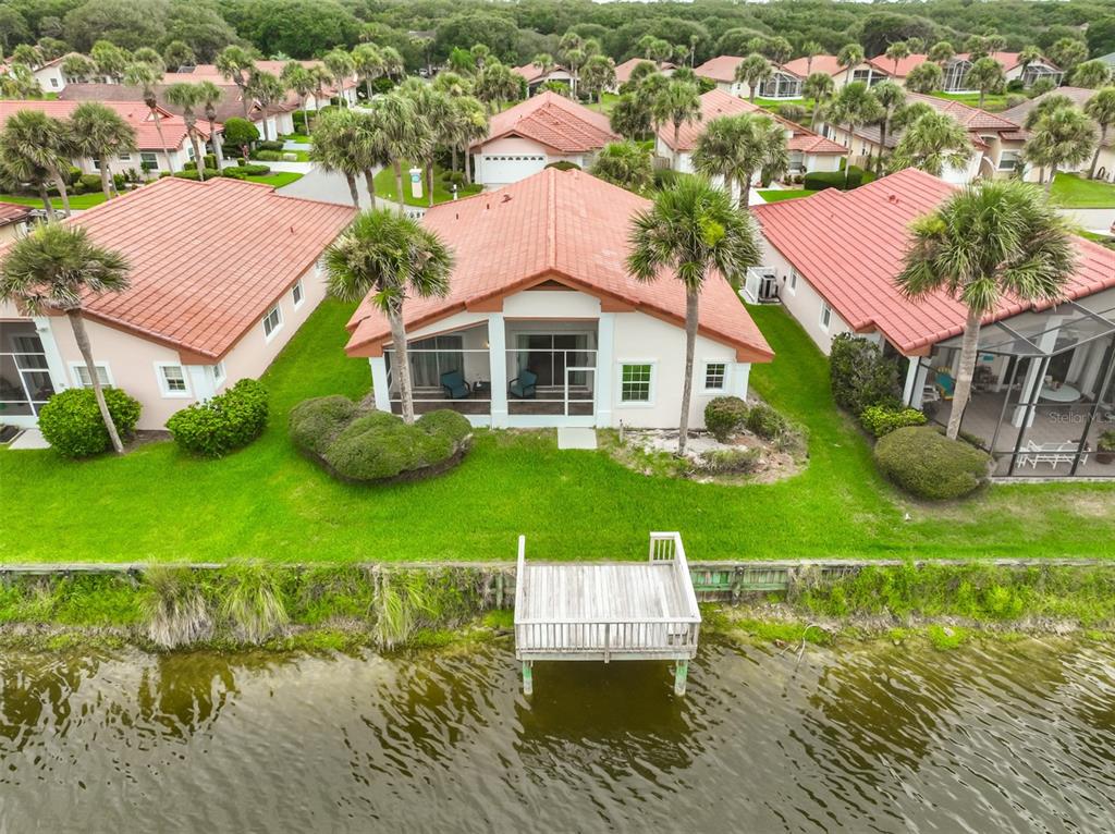 An aerial view of a waterfront house with a red tile roof and wooden dock — 18 SAN RAFAEL COURT, PALM COAST, FL