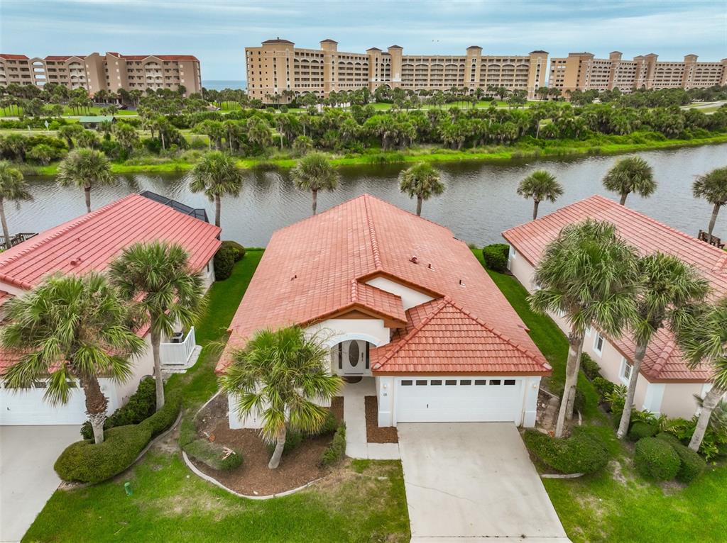 An aerial view shows a single-story house with a red tile roof near a canal — 18 SAN RAFAEL COURT, PALM COAST, FL