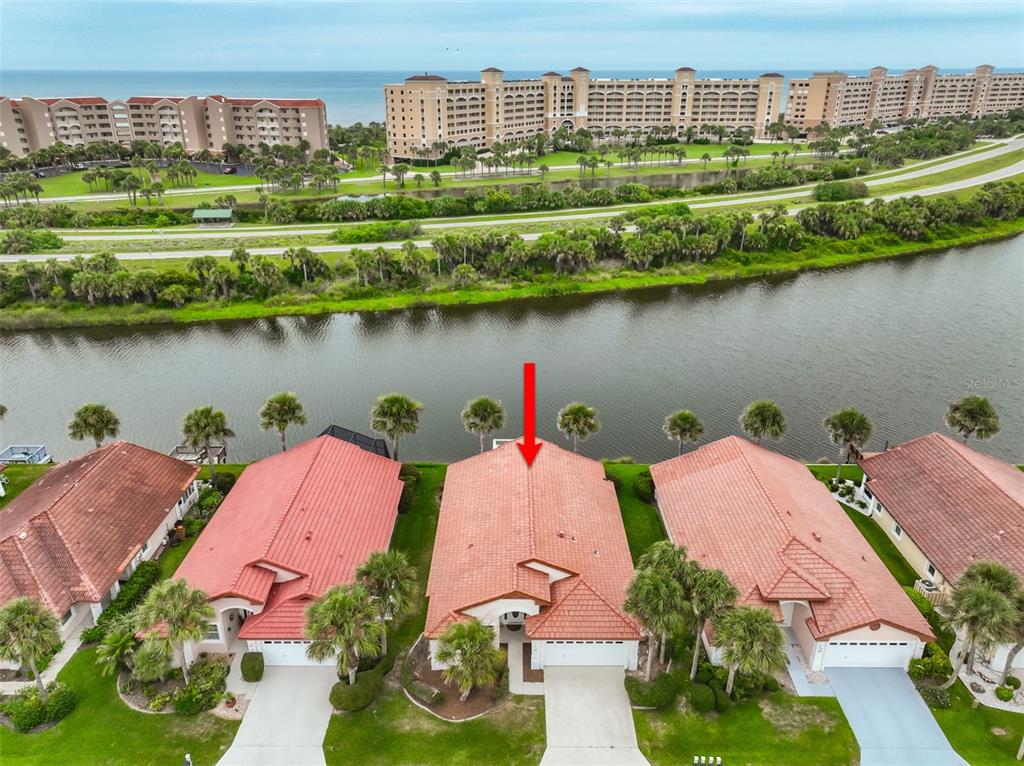 An aerial view shows a row of houses with red tile roofs near a canal — 18 SAN RAFAEL COURT, PALM COAST, FL