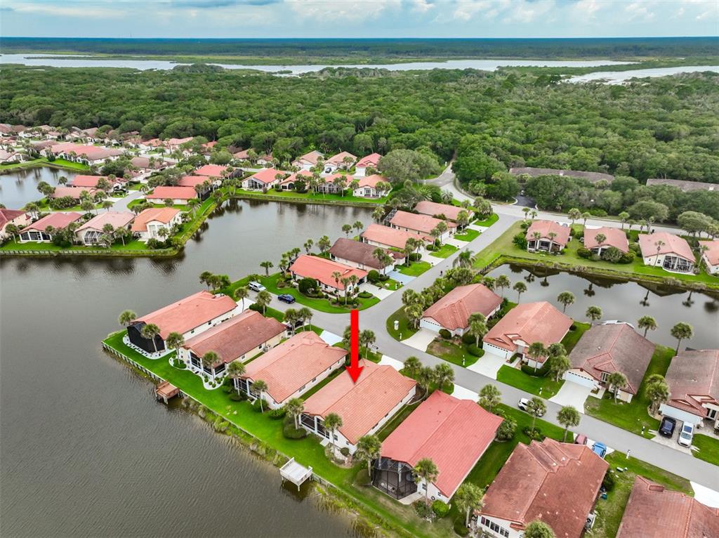 An aerial view shows a residential neighborhood with houses featuring red tile roofs near water — 18 SAN RAFAEL COURT, PALM COAST, FL