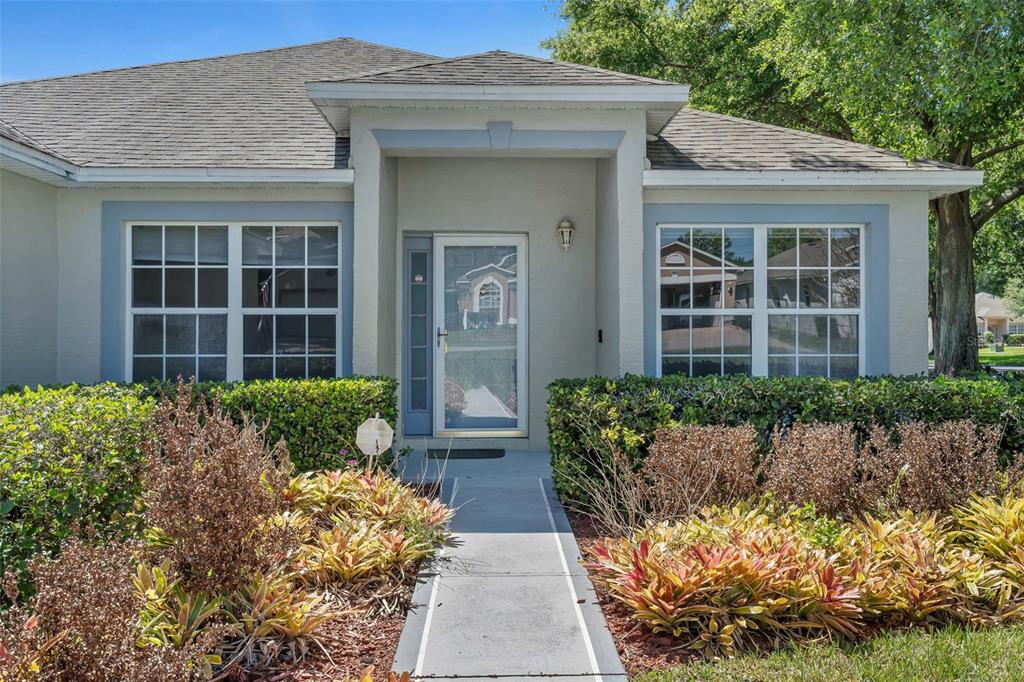 The exterior of a single-story house features a concrete walkway leading to the front door — 3871 EVERSHOLT STREET, CLERMONT, FL