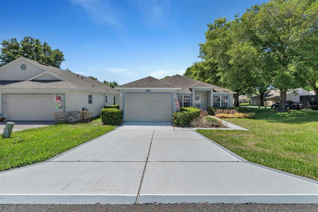 A single-story house with a two-car garage, concrete driveway, and a small front yard — 3871 EVERSHOLT STREET, CLERMONT, FL