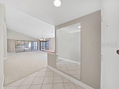 An entryway with tile flooring leads to a carpeted living area with sliding glass doors — 700 STARKEY ROAD UNIT 422, LARGO, FL