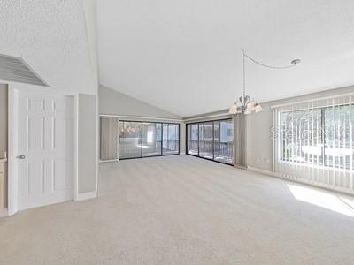 A spacious living room with vaulted ceilings, beige carpeting, and large sliding glass doors — 700 STARKEY ROAD UNIT 422, LARGO, FL
