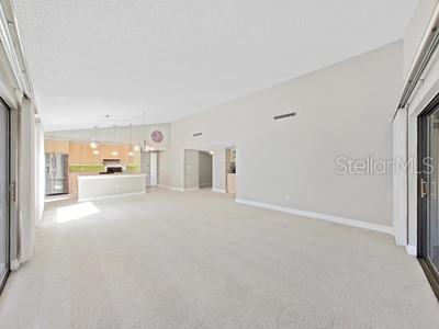 A spacious living room with beige carpet leads to an open kitchen with a breakfast bar — 700 STARKEY ROAD UNIT 422, LARGO, FL