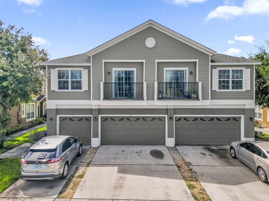 A two-story building with three garage doors, two upper-level balconies, and two parked cars — 1933 ESTANCIA CIRCLE UNIT 1933, KISSIMMEE, FL