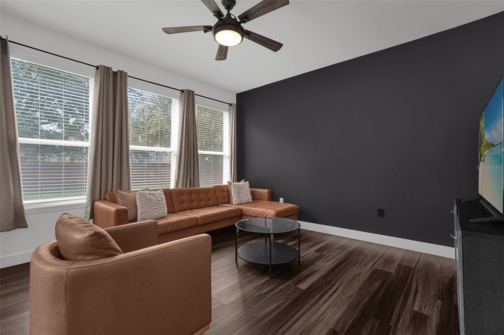 A living room features a brown sectional sofa, an armchair, and a dark accent wall — 1933 ESTANCIA CIRCLE UNIT 1933, KISSIMMEE, FL