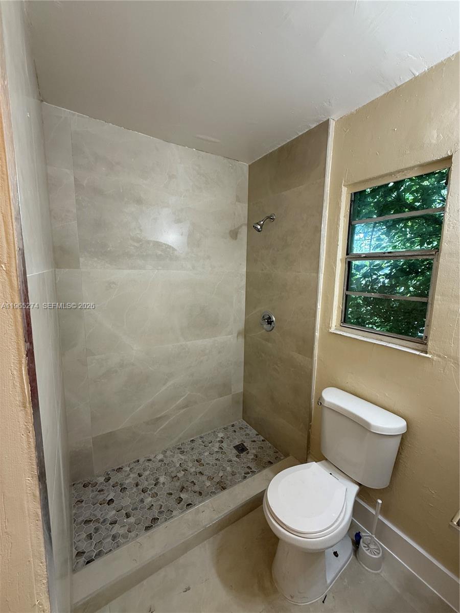 A bathroom features a tiled walk-in shower with a pebble floor next to a toilet — 8290 NW 4th Ave # 2, Miami FL 33150, MIAMI, FL