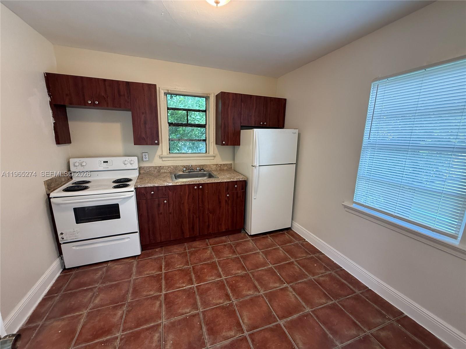 A kitchen features dark wood cabinets, a white stove, a white refrigerator, and tiled flooring — 8290 NW 4th Ave # 2, Miami FL 33150, MIAMI, FL