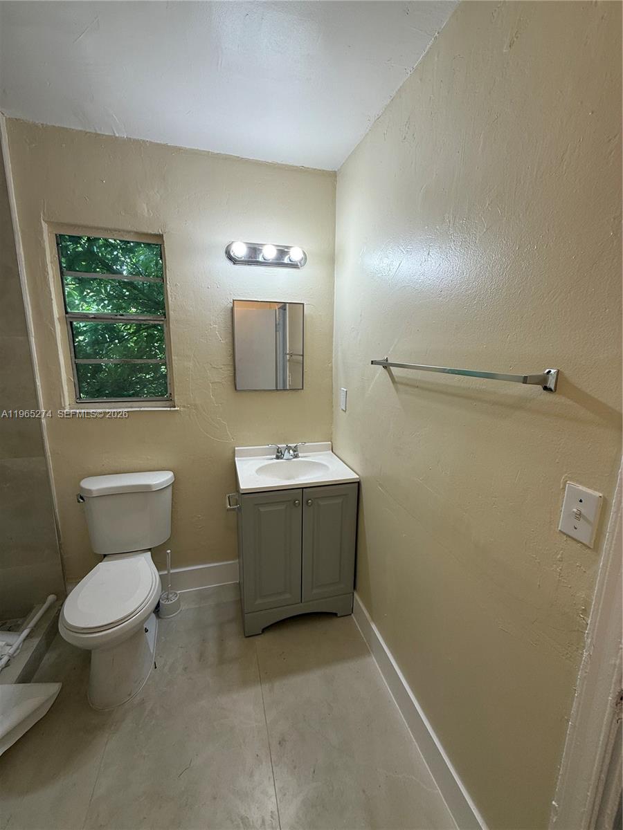 A bathroom features a toilet, a gray vanity with a sink, and a wall-mounted mirror — 8290 NW 4th Ave # 2, Miami FL 33150, MIAMI, FL