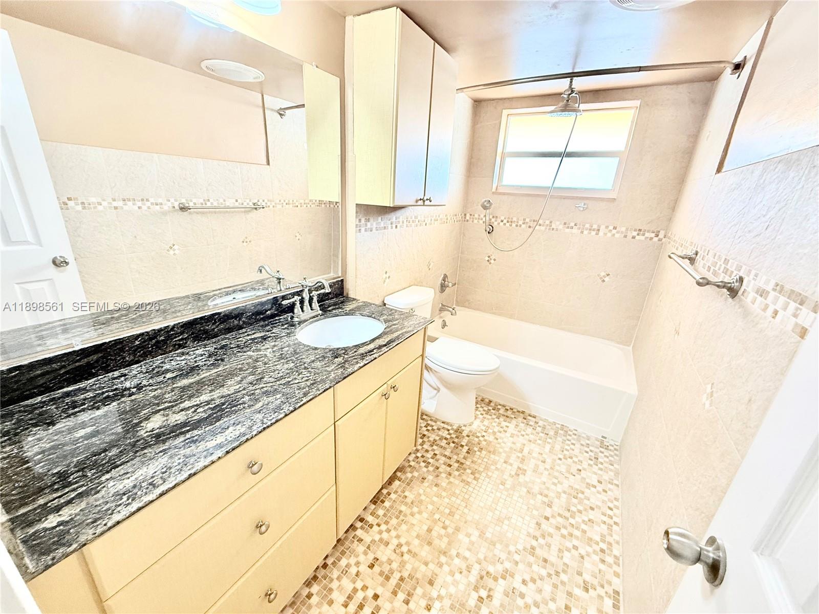 A bathroom features a granite vanity, light wood cabinets, and a tiled tub-shower combination — 3600 Harrison St # 16B, Hollywood FL 33021, HOLLYWOOD, FL