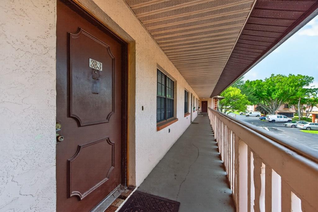 An exterior walkway leads to a brown door labeled 3B3 at a multi-story apartment building — 13250 RIDGE ROAD UNIT 3B3, LARGO, FL