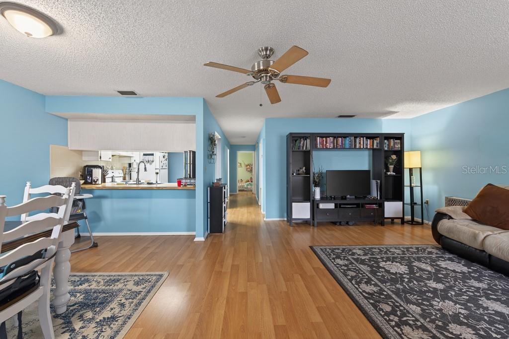 A living room and dining area with blue walls, wood-look flooring, and a ceiling fan — 13250 RIDGE ROAD UNIT 3B3, LARGO, FL
