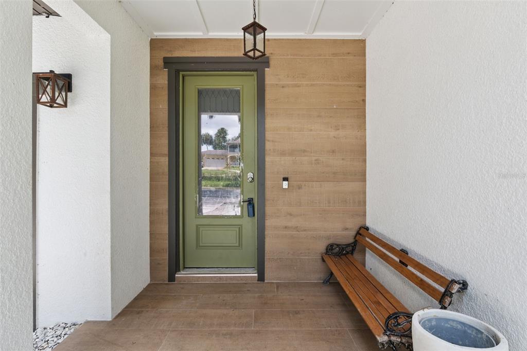 An entryway features a green door, wood-look siding, a wooden bench, and tiled flooring — 215 SUNRISE BOULEVARD, DEBARY, FL