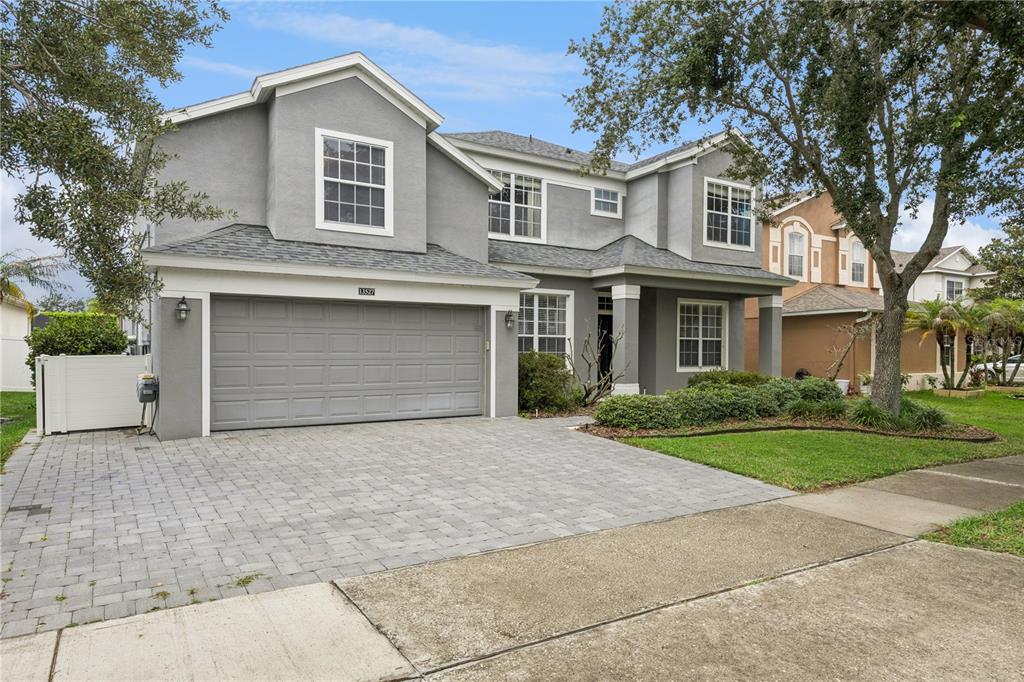A two-story gray house with a paved driveway, a two-car garage, and a front lawn — 13527 FOX GLOVE STREET, WINTER GARDEN, FL