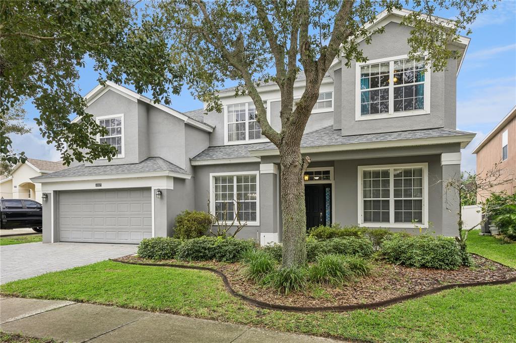 A two-story gray house with a two-car garage, a front lawn, and a large tree — 13527 FOX GLOVE STREET, WINTER GARDEN, FL