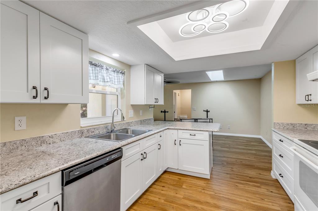 A kitchen with white cabinets, granite countertops, stainless steel appliances, and a recessed ceiling light — 704 GREEN ROAD, NEW SMYRNA BEACH, FL
