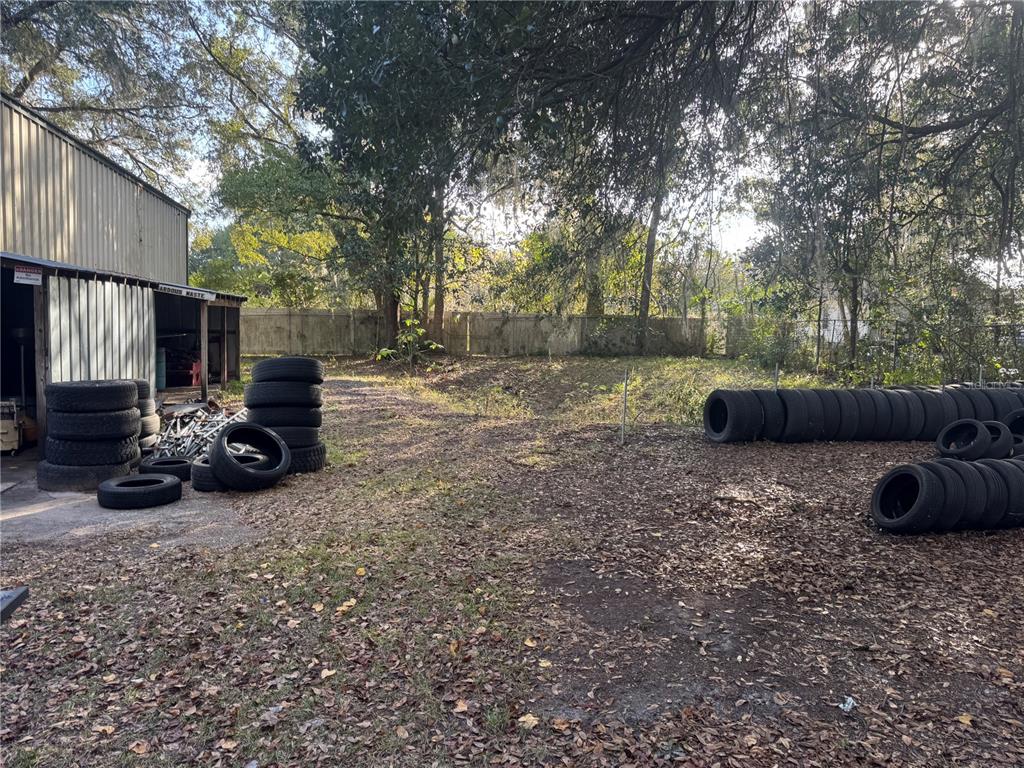 An outdoor area features a metal building and numerous stacked tires on a dirt lot — 15050 NE US HIGHWAY 301, WALDO, FL
