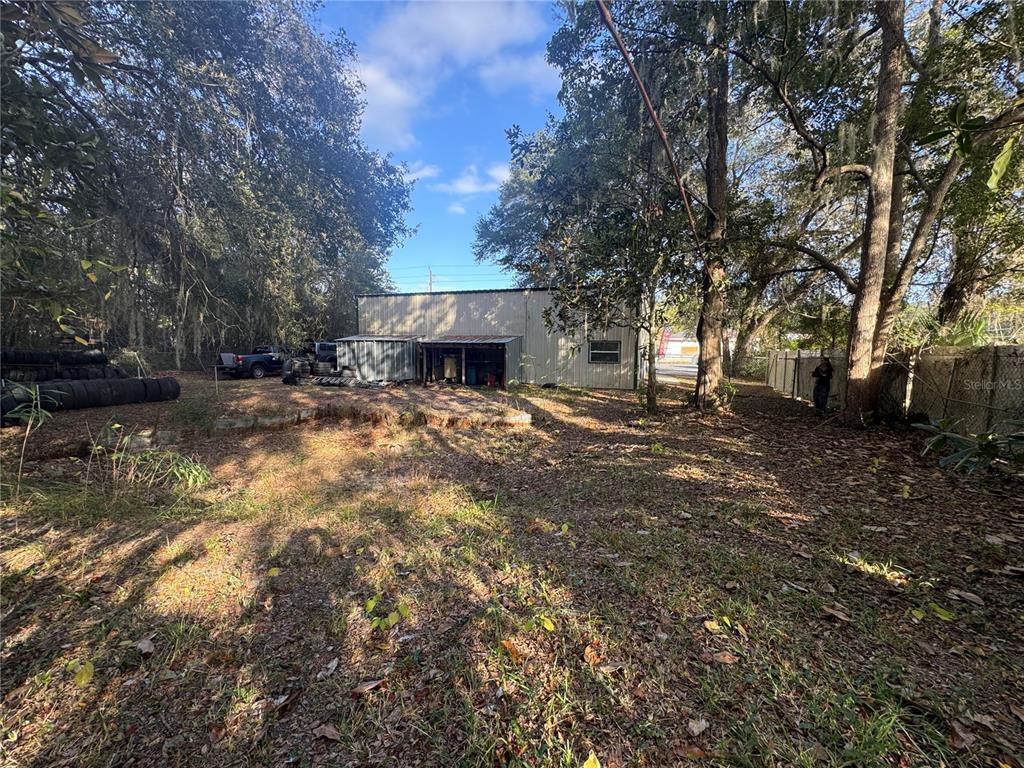 A metal workshop building sits on a wooded lot with a stack of tires nearby — 15050 NE US HIGHWAY 301, WALDO, FL