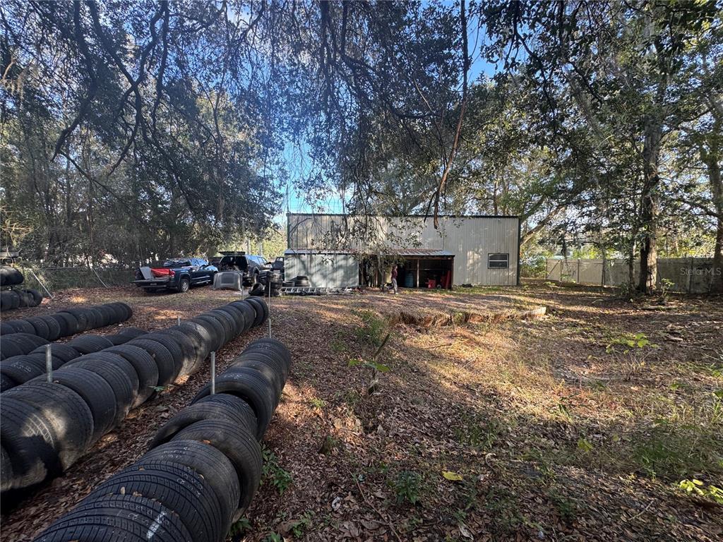 A large metal workshop sits on a wooded lot with many tires stacked outdoors — 15050 NE US HIGHWAY 301, WALDO, FL