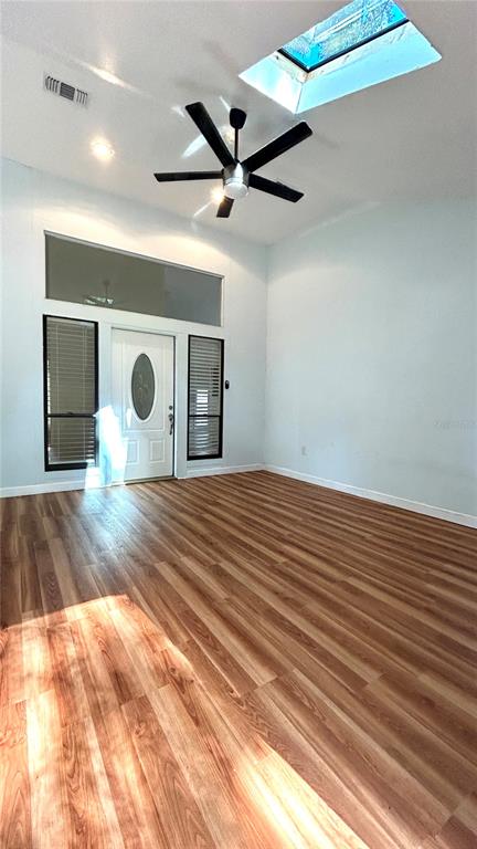 A bright room features wood-look flooring, a ceiling fan, a skylight, and a white door — 1034 SW 79TH TERRACE, GAINESVILLE, FL