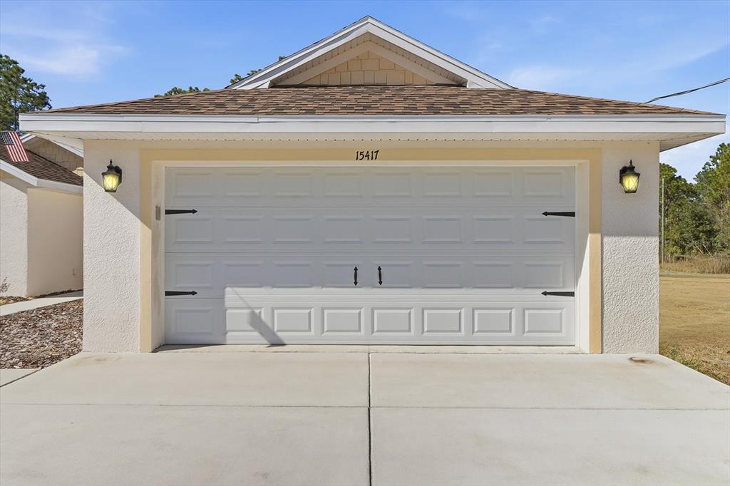 A white two-car garage with a gable roof and exterior wall-mounted lanterns — 15417 COOT ROAD, BROOKSVILLE, FL