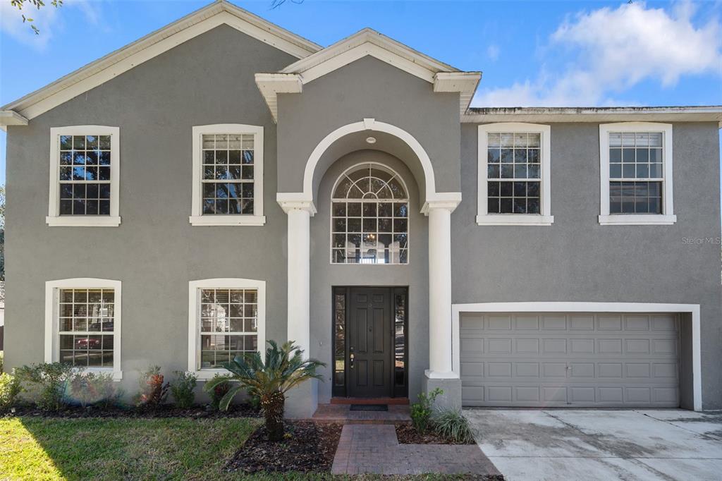 A two-story gray house with a prominent arched entryway, white columns, and a two-car garage — 1542 MCCREA DRIVE, LUTZ, FL