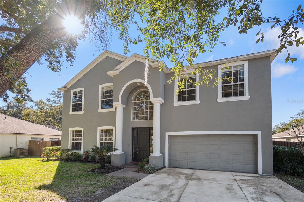 A two-story gray house with a two-car garage, arched entryway, and white columns — 1542 MCCREA DRIVE, LUTZ, FL