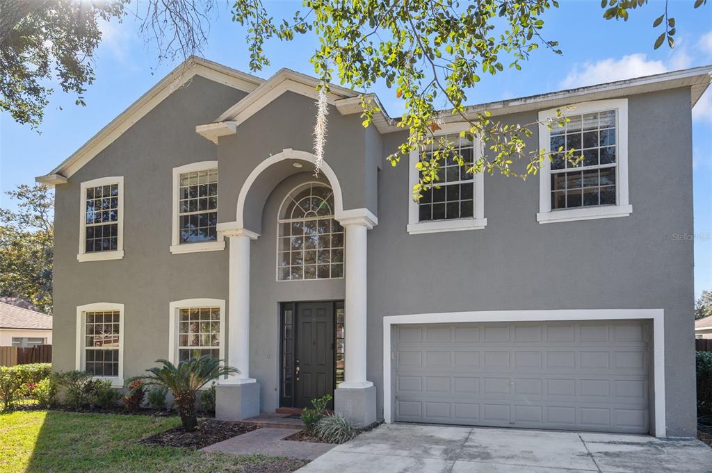 A two-story gray house with a two-car garage and a columned arched entryway — 1542 MCCREA DRIVE, LUTZ, FL