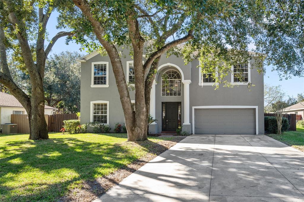 A two-story gray house with a two-car garage and a large tree in the yard — 1542 MCCREA DRIVE, LUTZ, FL