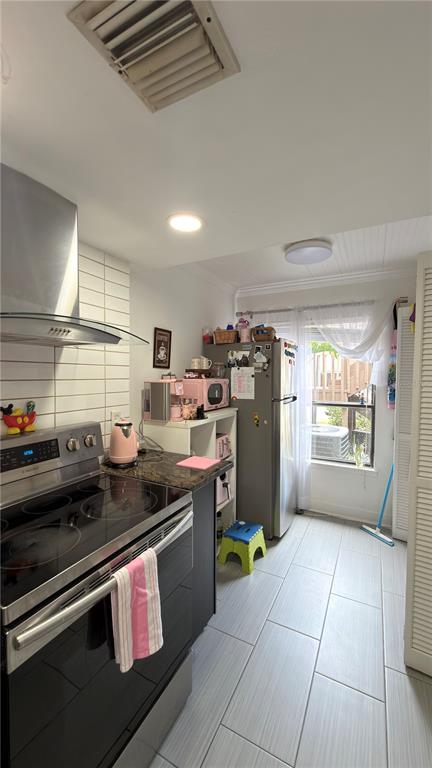 A kitchen featuring a stainless steel range, a refrigerator, and light-colored tile flooring — 5308 JASMINE CREEK LANE UNIT 1308A, ORLANDO, FL