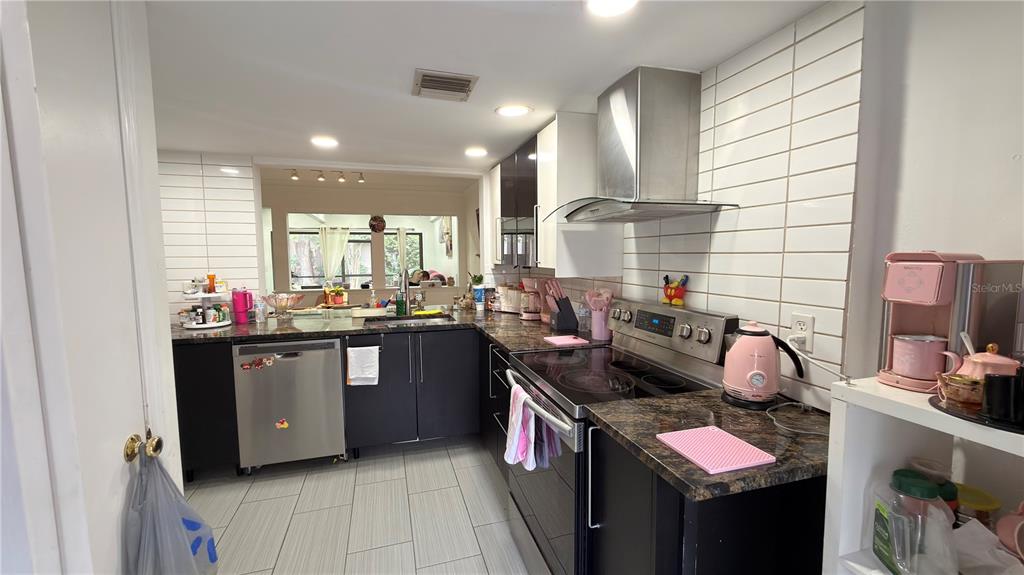A kitchen features dark cabinets, granite countertops, stainless steel appliances, and white subway tile backsplashes — 5308 JASMINE CREEK LANE UNIT 1308A, ORLANDO, FL