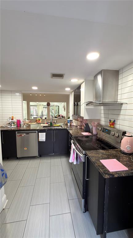 A kitchen with dark cabinets, granite countertops, stainless steel appliances, and light-colored tile flooring — 5308 JASMINE CREEK LANE UNIT 1308A, ORLANDO, FL