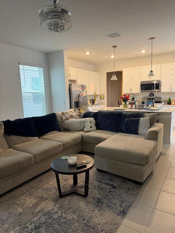 An open-concept living room features a large sectional sofa, a coffee table, and a kitchen — 1892 BRIGHT SKY DRIVE, KISSIMMEE, FL