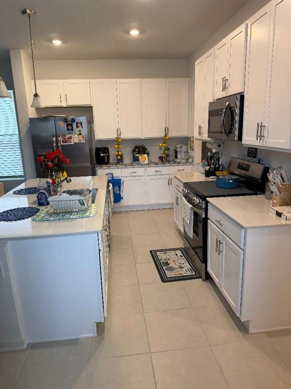 A kitchen features white cabinetry, stainless steel appliances, a large island, and light tile flooring — 1892 BRIGHT SKY DRIVE, KISSIMMEE, FL