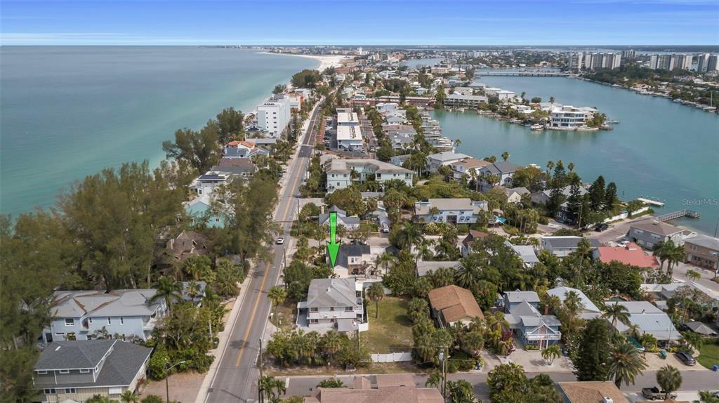 An aerial view shows a coastal neighborhood with a house highlighted by a green arrow — 8301 W GULF BOULEVARD, TREASURE ISLAND, FL