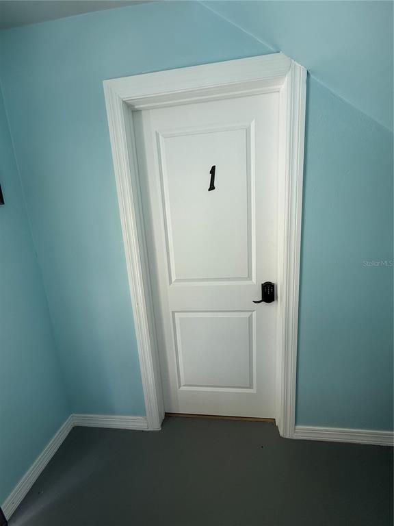 A white door labeled with the number one is set against light blue walls — 8301 W GULF BOULEVARD, TREASURE ISLAND, FL