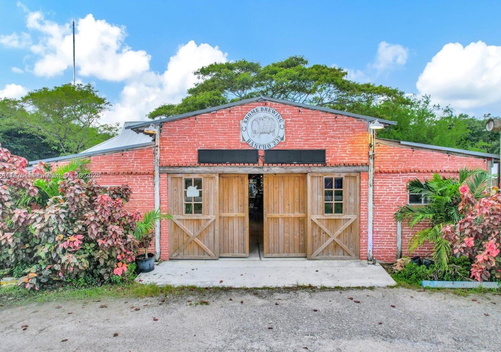 A red brick building with wooden barn-style doors and a circular brewery sign above — 17480 SW 232nd St, Miami FL 33170, MIAMI, FL