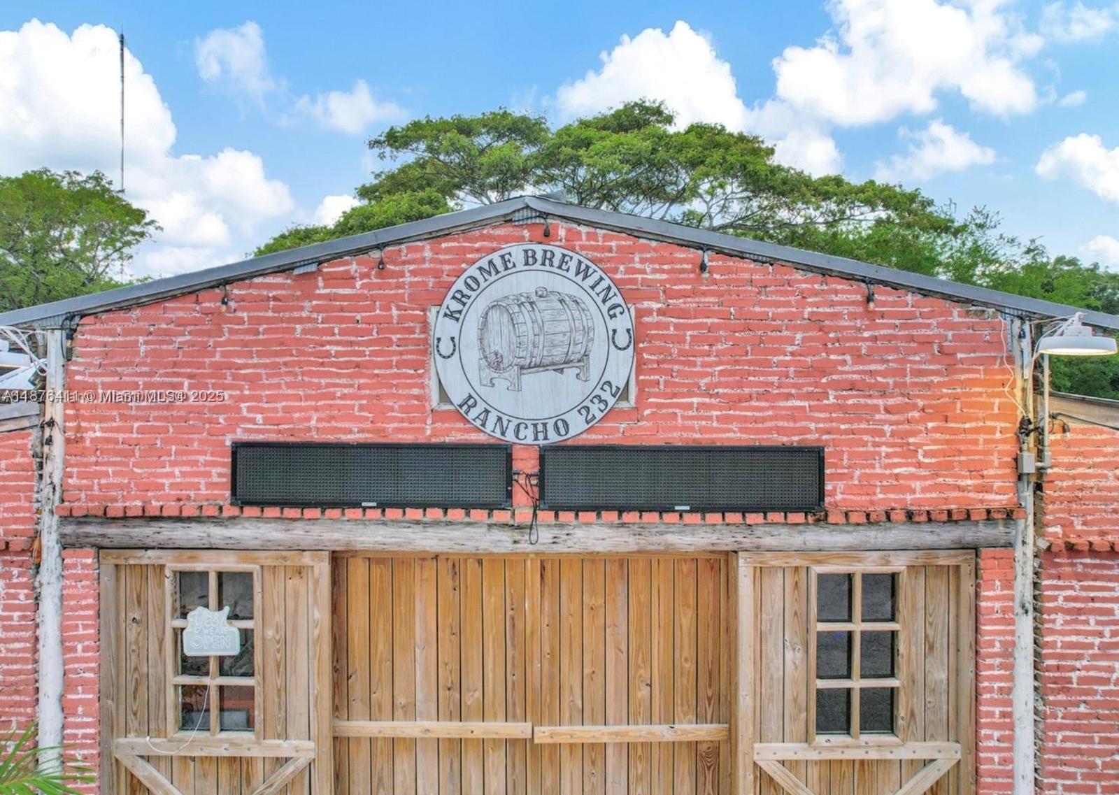 The exterior of a brick building features a wooden double door and a brewery sign — 17480 SW 232nd St, Miami FL 33170, MIAMI, FL