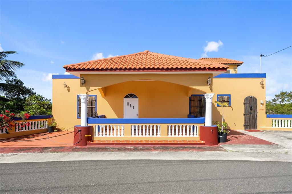 A yellow house with a covered porch, white columns, and a terracotta tiled roof — Km 15 H 7 PR 115 VILLA LA JOLLA, RINCON, PR