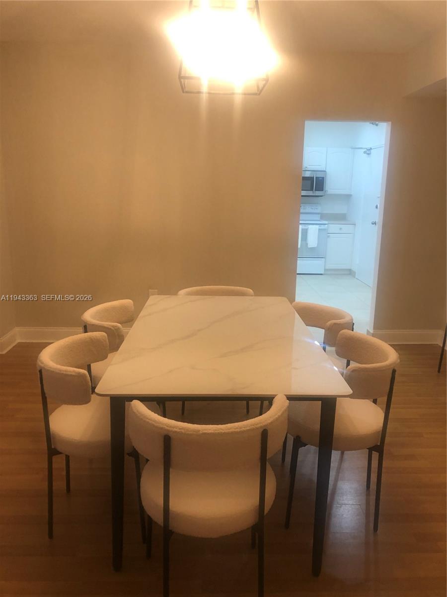 A dining room features a white marble-topped table with six upholstered chairs under a light — 10185 Collins Ave # 1016, Bal Harbour FL 33154, BAL HARBOUR, FL
