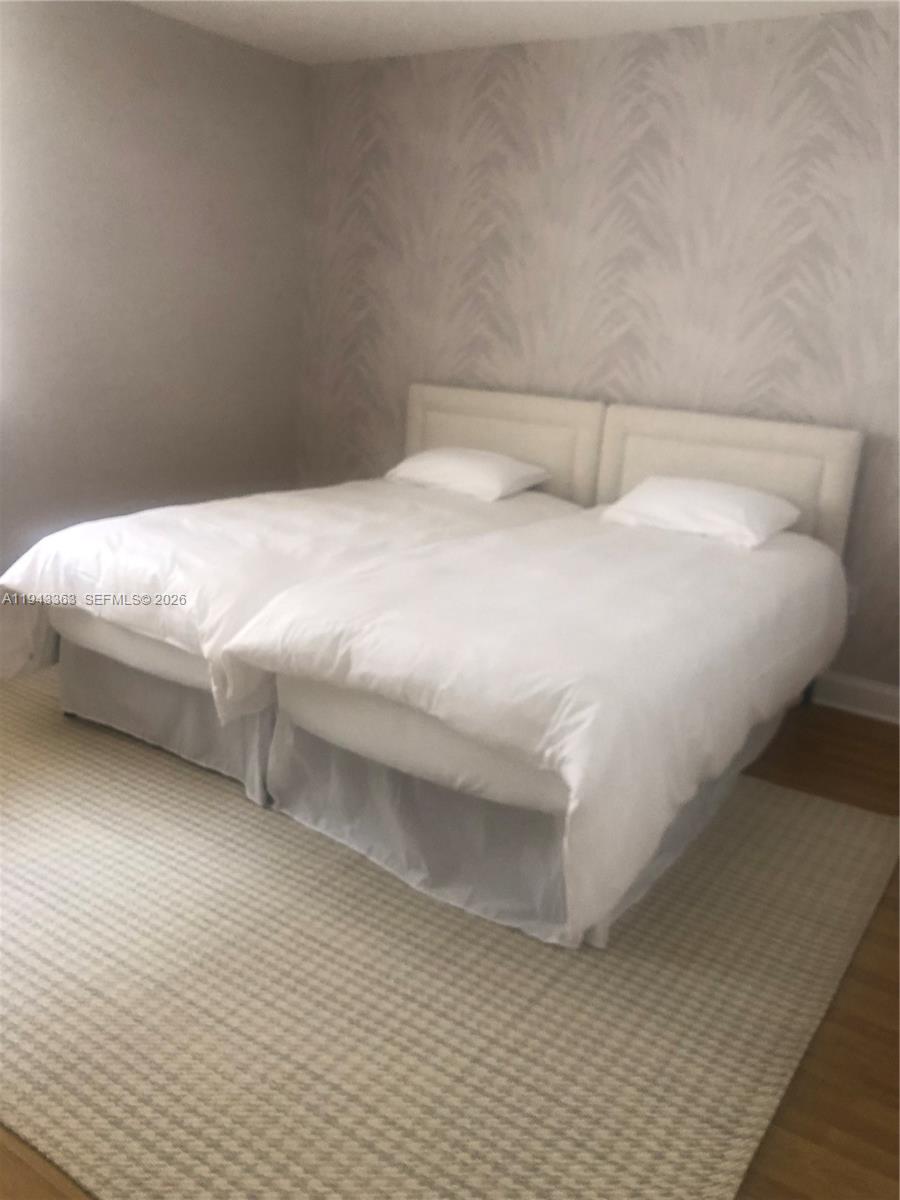 A bedroom features two twin beds pushed together against a patterned accent wall — 10185 Collins Ave # 1016, Bal Harbour FL 33154, BAL HARBOUR, FL