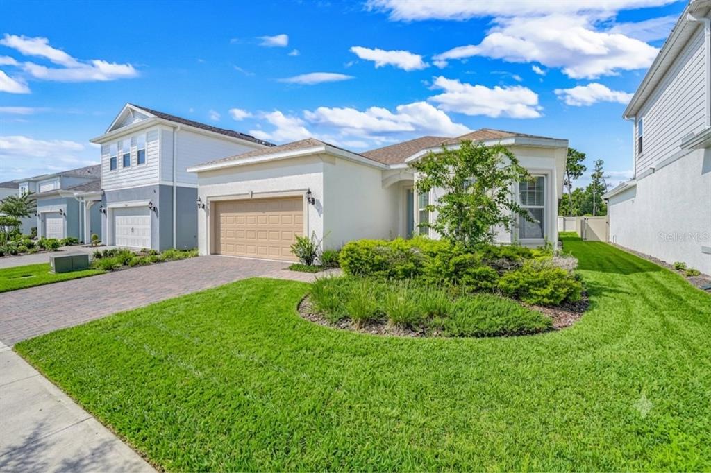 A single-story house with a tan garage, beige stucco exterior, and a landscaped front yard — 10393 PARK ESTATES AVENUE, ORLANDO, FL