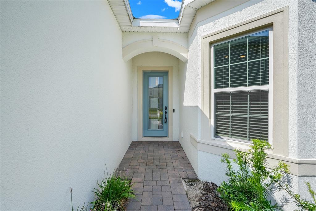 A paved walkway leads to a light blue front door under a small covered entryway — 10393 PARK ESTATES AVENUE, ORLANDO, FL