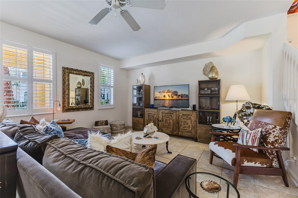 A living room features a brown sectional sofa, a television console, and a patterned armchair — 1564 NAPOLI DRIVE W, SARASOTA, FL