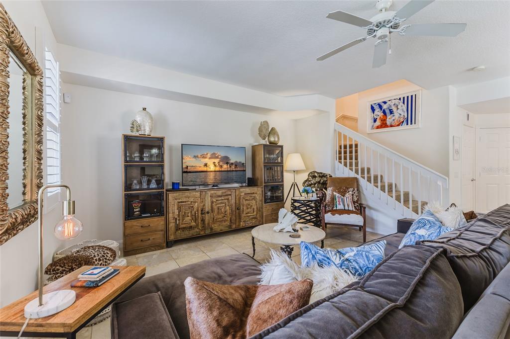 A living room features a large sectional sofa, a media console, and a staircase — 1564 NAPOLI DRIVE W, SARASOTA, FL