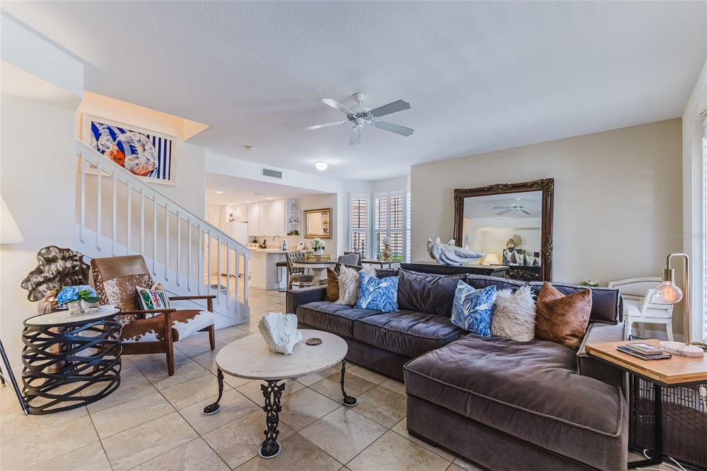 A living room features a large sectional sofa, a round coffee table, and a staircase — 1564 NAPOLI DRIVE W, SARASOTA, FL