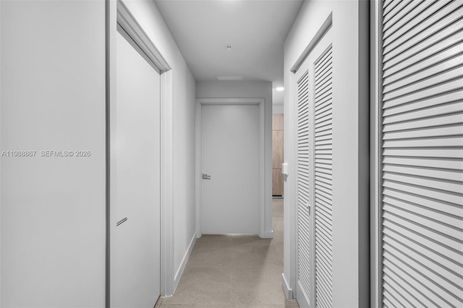 A narrow hallway features white walls, light tile flooring, and several closed interior doors — 11 NE 6th # 2207, Miami FL 33131, MIAMI, FL