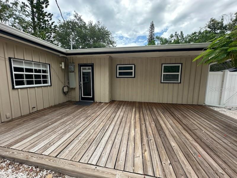 A wooden deck extends from the side of a tan house with vertical siding — 2559 E PAULSTAN COURT, SARASOTA, FL
