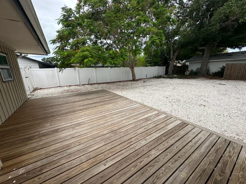 A wooden deck leads to a gravel backyard enclosed by a white vinyl fence — 2559 E PAULSTAN COURT, SARASOTA, FL